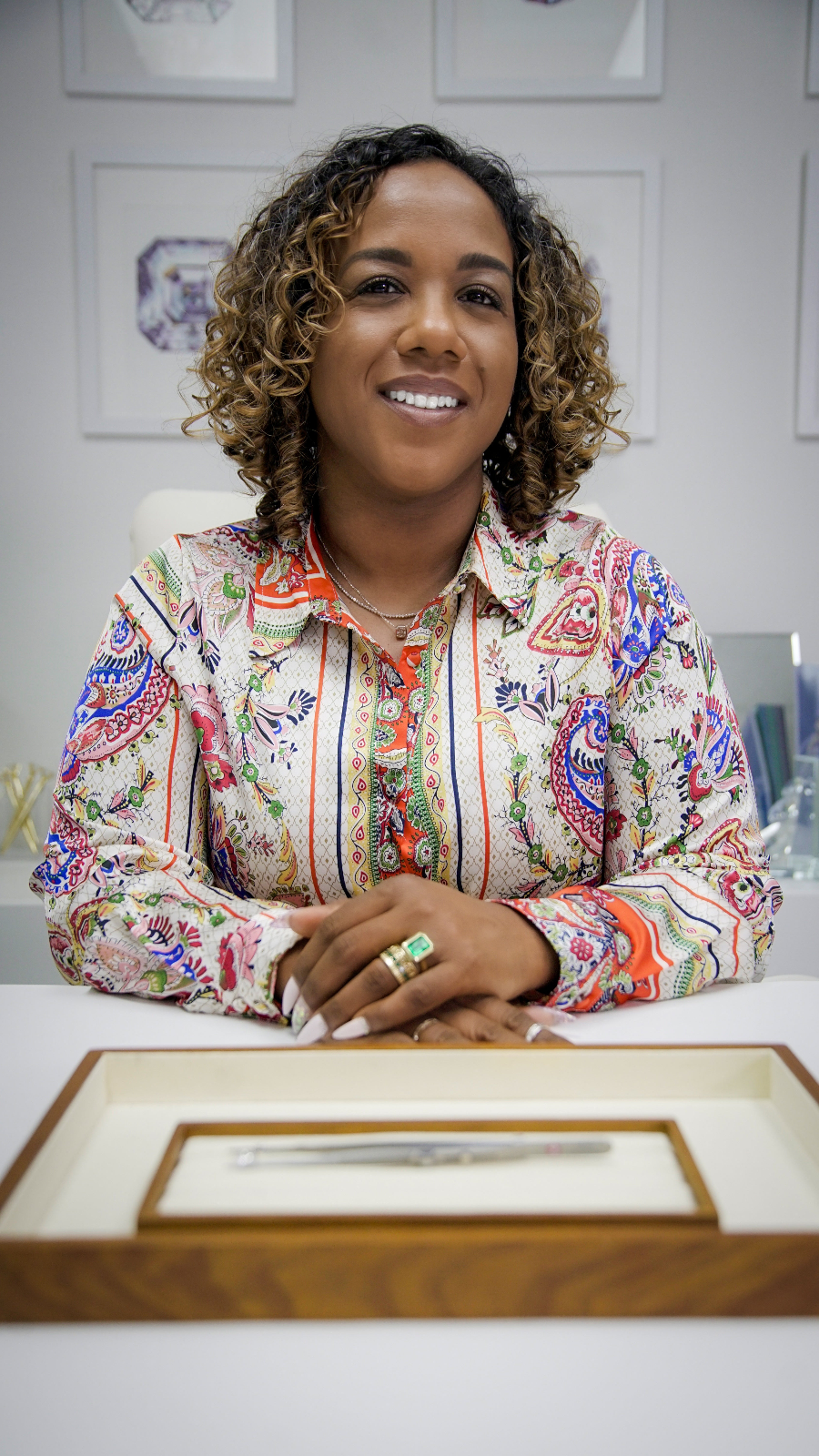 Woman in a colorful shirt sitting at a table with a framed document in front of her.