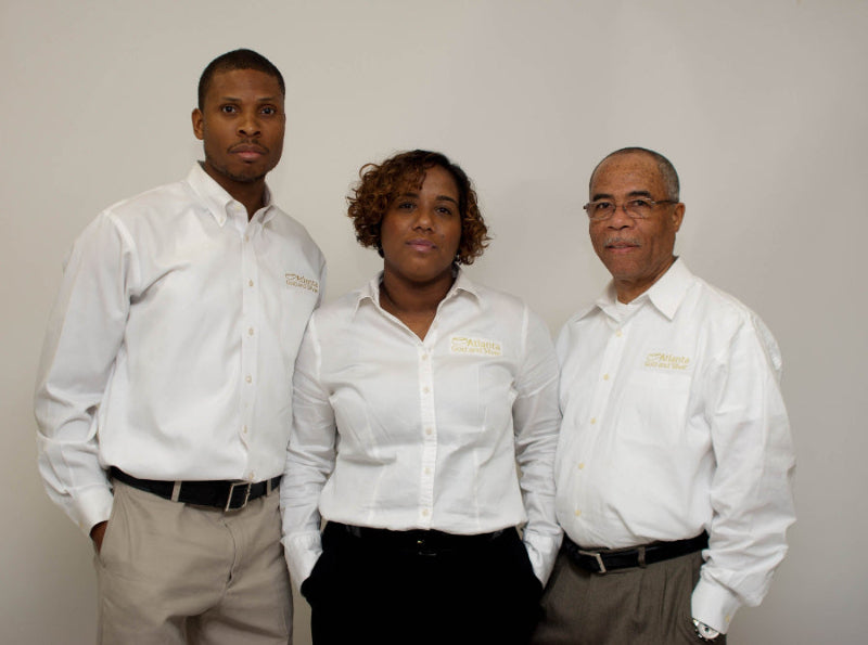 Three people wearing matching white shirts with a logo on a plain background