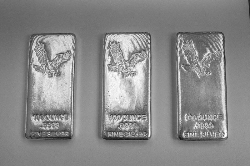 Three silver bars with eagle emblem and '100 ounces' text on a gray background