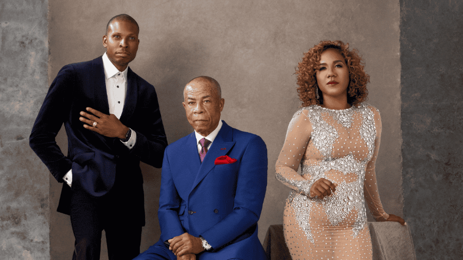 Three formally dressed individuals standing against a neutral background